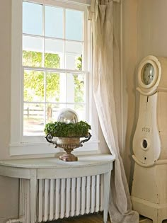 a white table with a potted plant on it next to a window