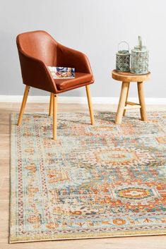 two chairs and a table on a wooden floor in front of a wall with a painting