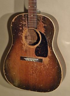 an old, worn out acoustic guitar is hanging on the wall in front of a white background