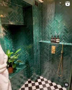 a green tiled bathroom with black and white checkerboard flooring on the shower