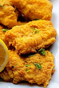 fried chicken with lemon wedges on a white plate