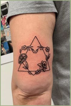 a black and white photo of a tattoo on the thigh with flowers around it's edges