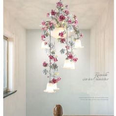 a chandelier with pink flowers hanging from it's sides in a room