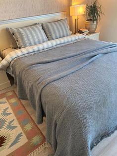 a bedroom with a bed, nightstands and rug on the floor in front of it