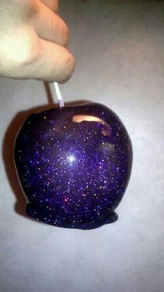 an apple with purple speckles on it being held by a person