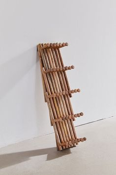 a sculpture made out of wooden sticks on the floor next to a wall with a white background