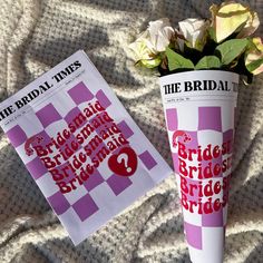 two paper cups sitting on top of a bed next to each other with flowers in them