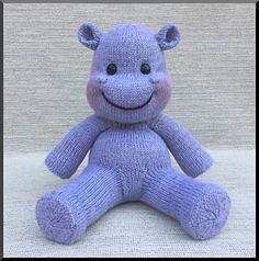 a purple teddy bear with a smile on it's face and eyes sitting down