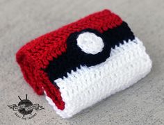 a red, white and black crocheted pouch sitting on top of a table