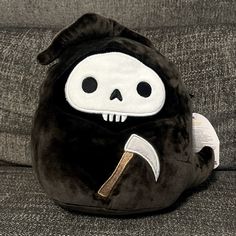 a stuffed animal with a knife in its mouth sitting on a gray couch next to a pillow