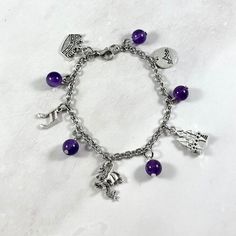 "This \"Long Live\" themed charm bracelet is the perfect accessory to showcase your love for our favorite pop star in a subtle way. Charms included: Crown Music Note Dragon Castle Mountians 5 purple amethyst beads  Comes in three sizes: Small: 6.5 inches (with extra rings at the end to expand up to 7.5 inches.) Standard: 7.5 inches Large: 8.5 inches Secures with a lobster clasp. Chain is stainless steel. Charms are made with zinc alloy. Beads are natural gemstones. All materials are lead and nickel free.  Comes in a jewelry box so it would be ready to be given as a gift! Message me of you would like to substitute any of the charms. If you have any questions or need more quantities than are currently available, please message me. Warning: small parts. Not intended for small children." Personalized Purple Charm Bracelet For Friendship, Adjustable Purple Bracelets With Charms, Purple Metal Jewelry With Charms, Purple Charm Bracelet Gift, Adjustable Purple Metal Charm Bracelet, Adjustable Nickel-free Purple Charm Bracelet, Purple Amethyst Charm Bracelet For Gift, Purple Metal Beaded Bracelets As Gift, Purple Amethyst Charm Bracelet Gift