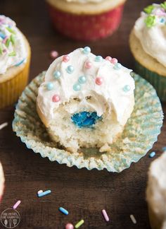 cupcakes with white frosting and sprinkles are on the table