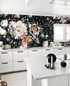 a kitchen with floral wallpaper and white cabinets