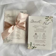 the wedding stationery is laid out on top of white paper and tied with a pink ribbon