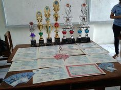 a woman standing in front of a table with trophies on it and papers all over the table