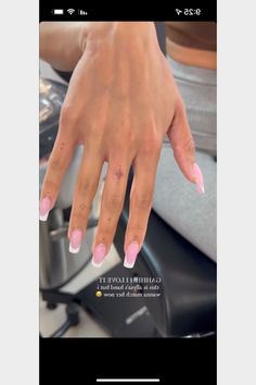 a woman's hand with pink and white nail polish on her nails, sitting in a car