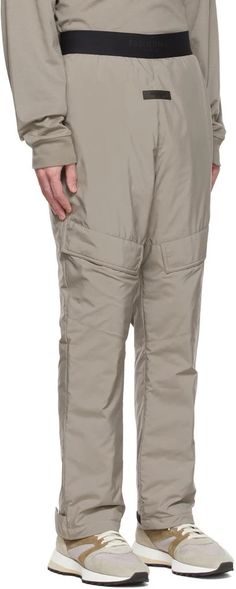 Fear of God ESSENTIALS.Taupe Polyester Cargo Pants.Insulated polyester satin cargo pants..· Logo bonded at elasticized waistband.· Rubberized logo patch at front.· Gusset at dropped inseam.· Flap pocket at legs.· Two-pocket styling.· Adjustable velcro tab at cuffs.· Fully lined.Please note that this item may not be shipped within the EU..Supplier color: Desert taupe.Body: 100% polyester. Fill: 100% polyester. Lining: 100% polyester..Made in China..221161M190043 Winter Utility Nylon Parachute Pants, Winter Utility Cargo Pants With Elastic Waistband, Outdoor Nylon Cargo Pants With Patch Pockets, Winter Nylon Parachute Pants With Pockets, Full Length Nylon Cargo Pants With Elastic Waistband, Winter Nylon Pants With Pockets, Winter Nylon Bottoms With Side Pockets, Khaki Nylon Bottoms With Cargo Pockets, Khaki Nylon Streetwear Bottoms