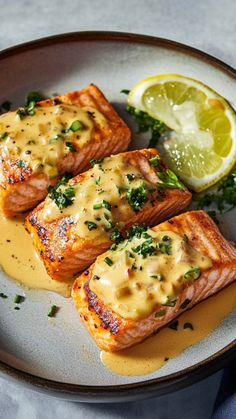 three salmon fillets on a plate with sauce and garnish