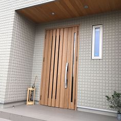 a wooden door sitting on the side of a white brick wall next to a plant