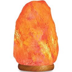 an orange himalayan salt lamp on a wooden base with a white back ground and light from the side