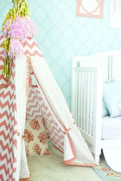 a pink and white teepee with flowers on it in the corner of a child's room