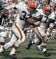 two football players are running with the ball in their hands as an opposing team looks on