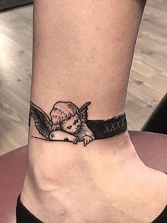 a small ankle tattoo with an angel on it