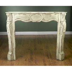 an old white painted fireplace mantel in a room with hard wood floors and green walls