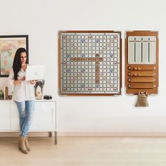 a woman standing in front of a white cabinet holding a laptop