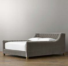 a bed that is sitting on top of a hard wood floor in front of a white wall