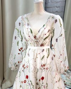 a white dress with red and green flowers on it