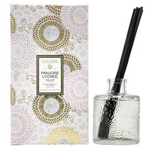 an empty glass bottle with a black straw in it next to a white box and flower pattern