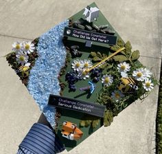 someone is holding up a graduation cap with flowers and other things on it that are in the shape of a triangle