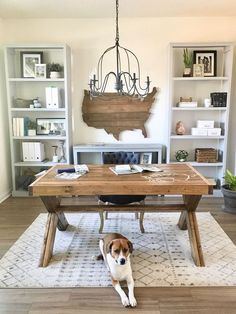 a dog laying on the floor in front of a wooden table with bookshelves