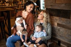 three women and two children sitting on a bench in a restaurant smiling at each other