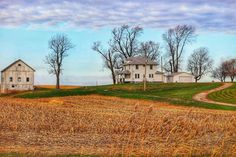 an old farm house sits in the middle of a field