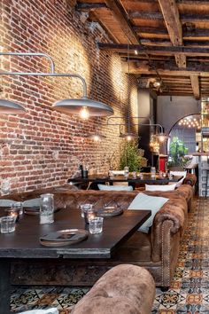 a brick wall in a restaurant with leather couches and tables set up for dining