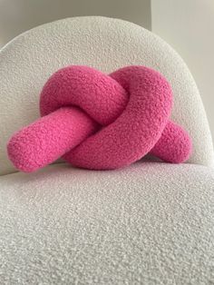 a pink knot sitting on top of a white chair