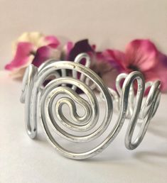 Gorgeous adjustable aluminum bracelet with intertwining spirals. Elegant, charming, bold and, beautifully hand-crafted. ♥ Lightweight  and easy to wear ♥ Stunning AND Bold ♥ This bracelet can be dressed up or down ♥ Molds to fit any wrist size ♥ Custom made to order - one-of-a-kind ♥ Made out of aluminum wire  ♥ Non-tarnishing and hypo-allergenic. This item is made by hand one at a time so there may be slight variations with each design.  This bracelet is made with aluminum so it will bend so you can get the correct size but won't keep bending while on your wrist. To care for your bracelet, remove the cuff before using soaps and cleaning products is recommended to extend the life of, and keep your jewelry looking new. Thanks for visiting my shop! I specialize in wire wrapping jewelry made Adjustable Metal Spiral Cuff Bracelet, Spiral Metal Cuff Bracelet As Gift, Spiral Silver Cuff Bracelet, Silver Spiral Metal Cuff Bracelet, Silver Spiral Cuff Bracelet Gift, Adjustable Spiral Silver Cuff Bracelet, Adjustable Silver Spiral Cuff Bracelet, Silver Spiral Bohemian Bracelets, African Beaded Bracelets