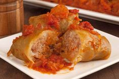 stuffed cabbage rolls with meat and tomato sauce on a white plate