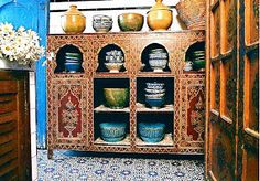 an old cabinet with vases and bowls on it