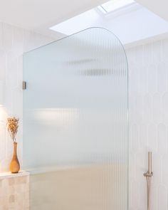 a glass shower door in a white bathroom