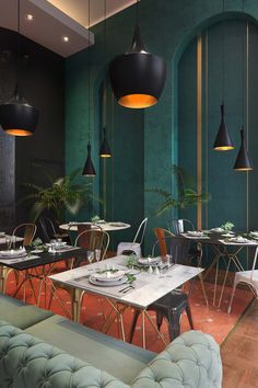 the interior of a restaurant with green walls and black lamps hanging from the ceiling over tables