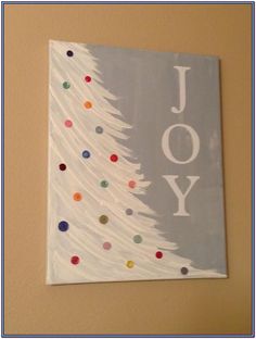 a white christmas tree with the word joy painted on it's side in front of a tan wall