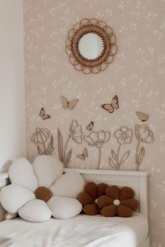 a white bed sitting under a mirror next to a wall with flowers and butterflies on it