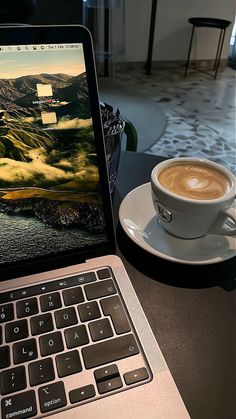 an open laptop computer sitting on top of a table next to a cup of coffee