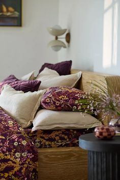 a bed with many pillows on top of it and a table in front of it