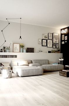 a living room filled with white furniture and pictures on the wall above it's fireplace