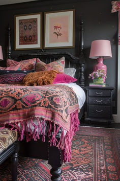 a bed with pink pillows and blankets on top of it next to two framed pictures