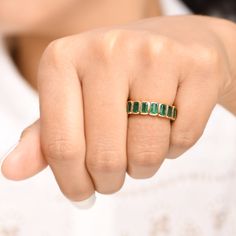 a close up of a person wearing a ring with emeralds on it's fingers